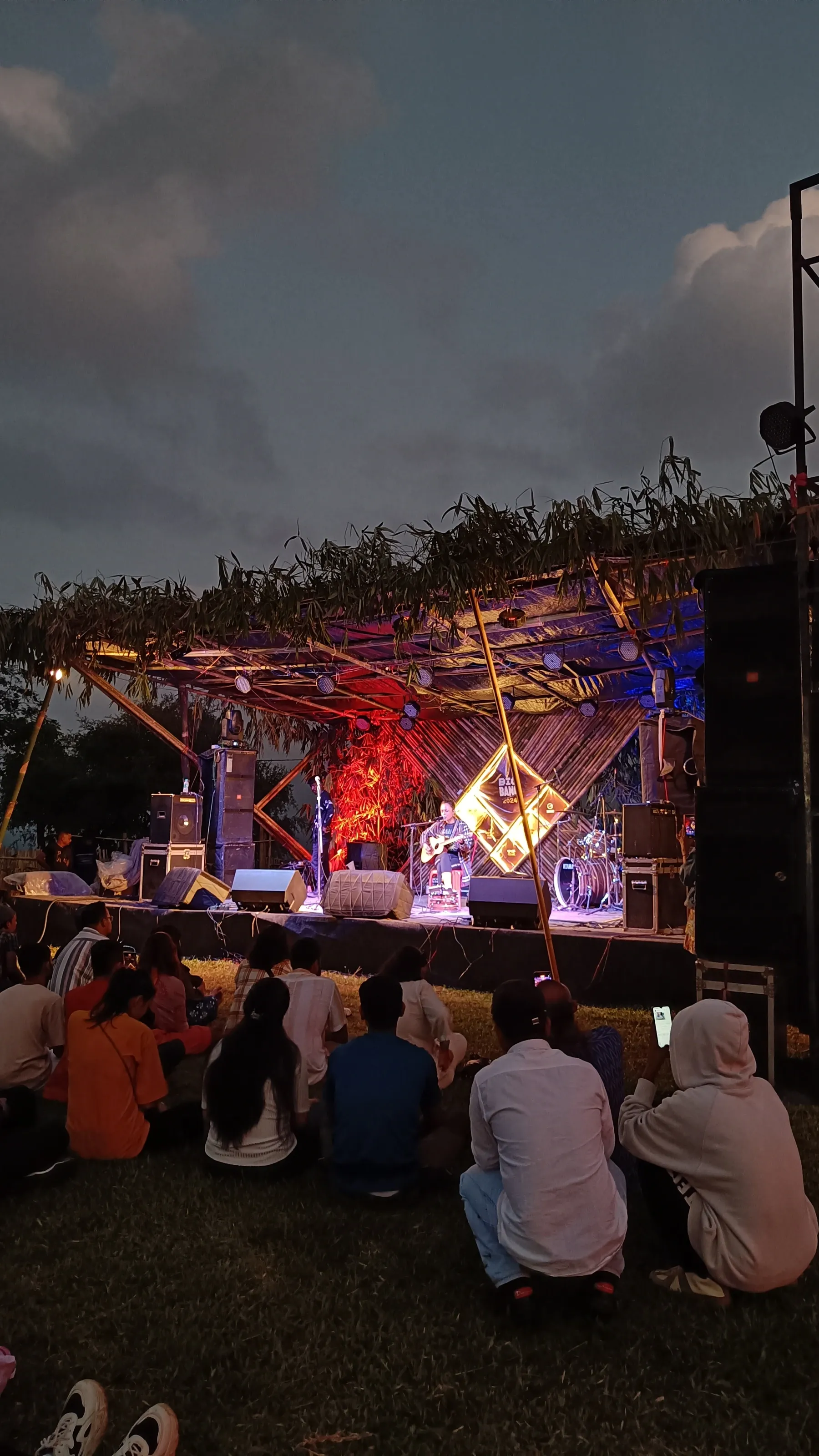 A performer on the bamboo main stage, lit in purple stage light